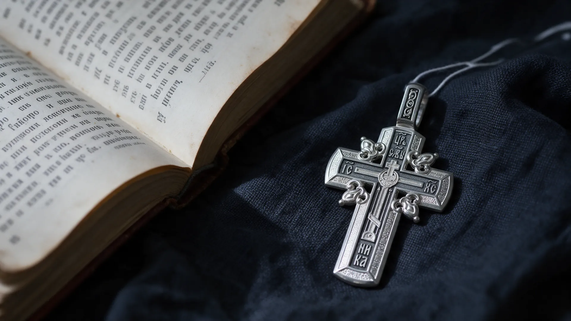Silver pectoral crucifix on linen beside a prayer book